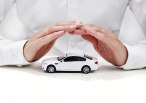 A man's hands covering a white toy car.
